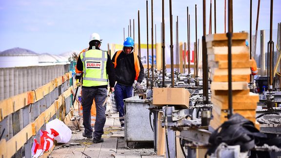 Twee mannen werken aan de bouw van windschermen als onderdeel van het Theemswegtracé