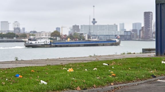 Barge in the Waalhaven in Rotterdam with a grass field with litter in the foreground