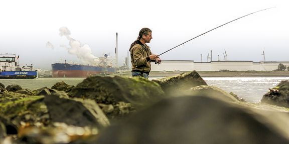 Man is aan het vissen in de haven