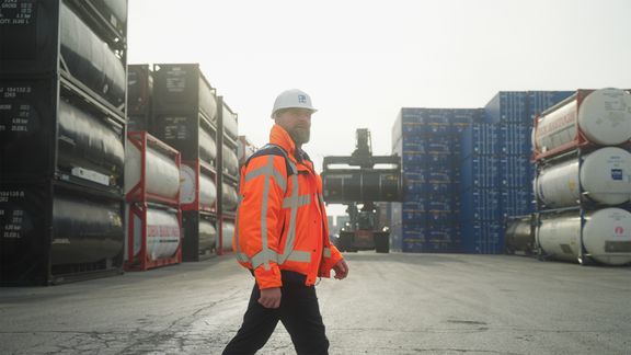 Ron Kuijpers lopend over het terrein van Broekman Logistics, met chemiecontainers op de achtergrond