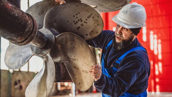 Man van scheepswerf De Haas werkt aan schroef