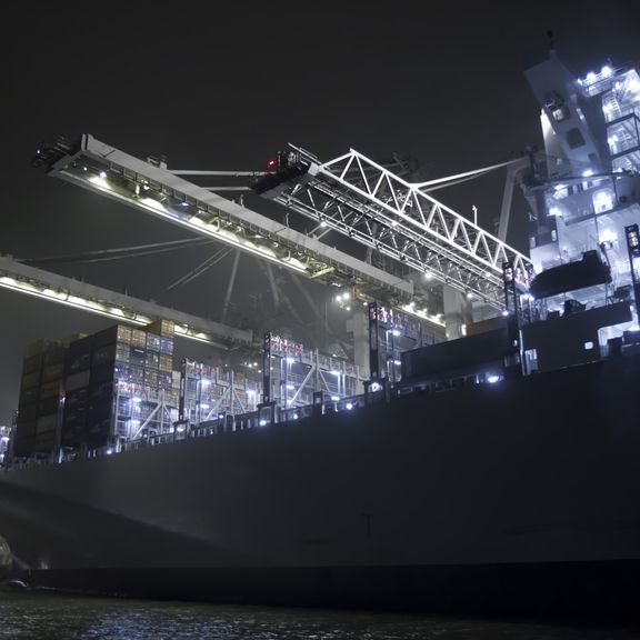 Containerschiff wird in der Nacht beladen