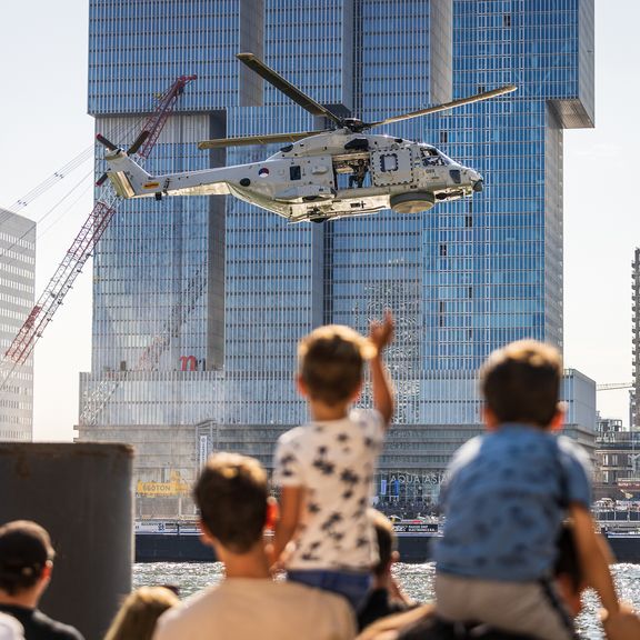 Boy waving to a helicopter on his fathers shoulders